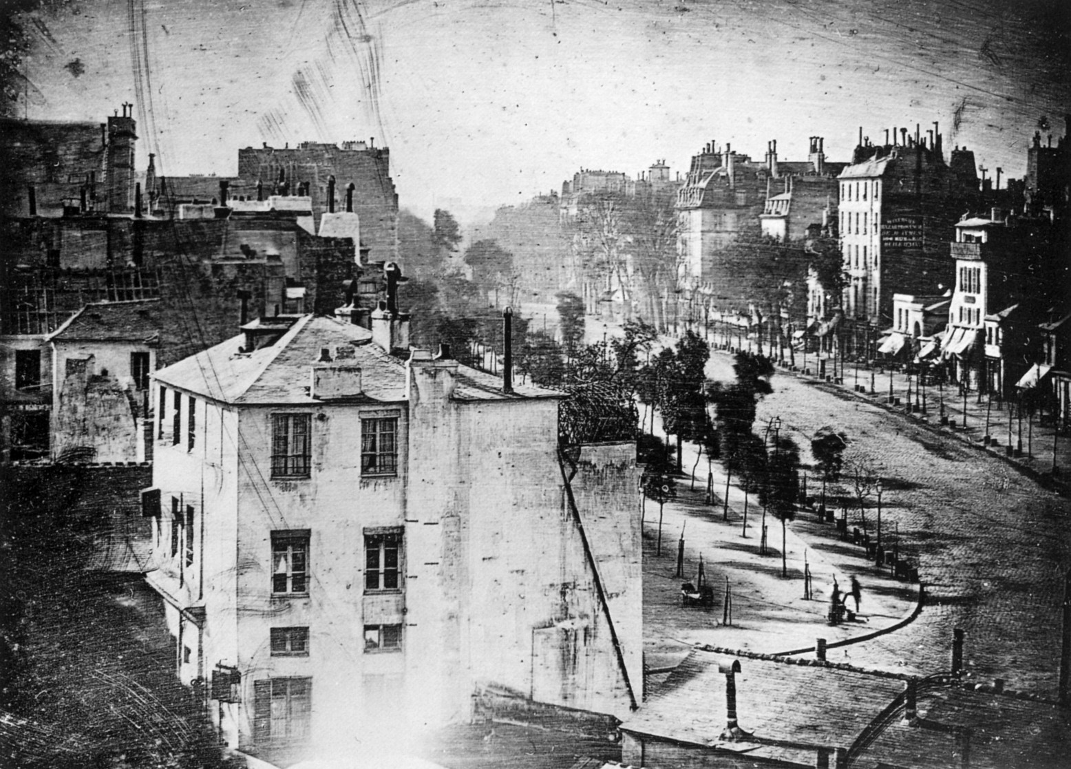A Daguerrotype of the Boulevard du Temple in Paris, made by Louis Daguerre in 1838. Due to the long exposure, nothing that was in motion was captured, but a standing figure who remained stationary (while getting his boots polished) can be seen.